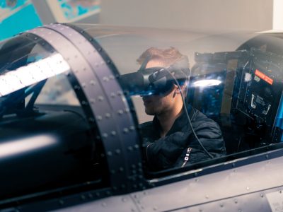 boy sitting in flight simulator military plane wearing virtual reality glasses during flight entertainment
